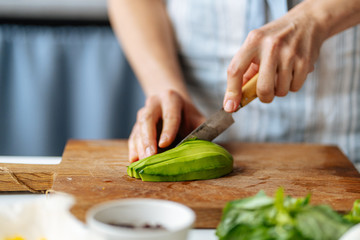 Woman cutting avocado on cutting board