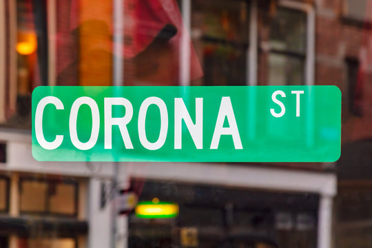 Green street sign on a window with the text corona street with reflections in the back