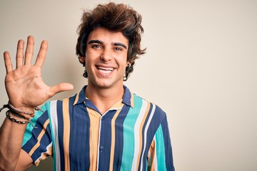 Young man on vacation wearing summer colorful shirt standing over isolated white background showing and pointing up with fingers number five while smiling confident and happy.