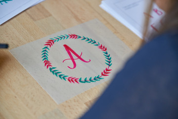 From above of drawn beautiful red letter A in colorful circle of twigs on wooden table 