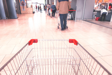 Line at supermarket people respecting social distancing measures  pov from empty shopping cart  - Concept of everyday life in the time of covid-19 pandemic - Image - obrazy, fototapety, plakaty