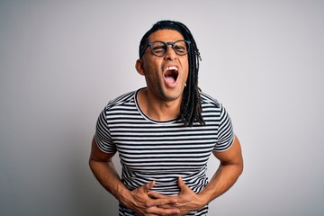 Young handsome african american man with dreadlocks wearing striped t-shirt and glasses with hand on stomach because nausea, painful disease feeling unwell. Ache concept.