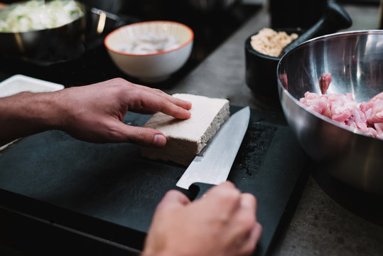 From above anonymous chef cutting piece of fresh cheese near bowl with meat during cooking lesson in restaurant kitchen in Navarre, Spain