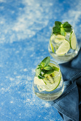 Two detox water or martini tonic cocktail with kiwi, lime, ice and mint. A new kind of mojito with...