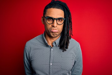 Obraz premium Young handsome african american man with dreadlocks wearing casual shirt and glasses depressed and worry for distress, crying angry and afraid. Sad expression.