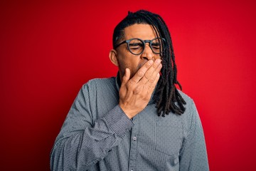Young handsome african american man with dreadlocks wearing casual shirt and glasses bored yawning tired covering mouth with hand. Restless and sleepiness.
