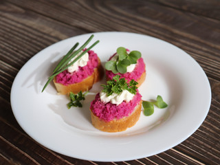 Beautiful sandwiches with pink and white pasta, fresh herbs on a white plate and wooden background.