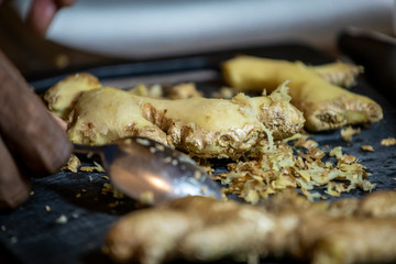 close up macro view of fresh organic ginger being cut and prepared for a health meal. the root extract is used in homemade health remedies from many cultures 