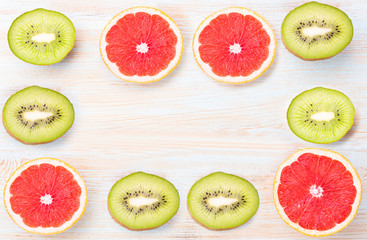 Top view of sliced citrus fruits grapefruit and kiwi on blue table.