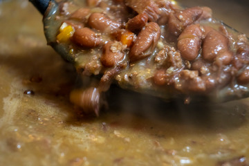 close up macro view of red beans and rice stew that was cooked for a tasty delicious dinner. the vegetables are vibrant with steam coming from the soup. a healthy organic meal was prepared.
