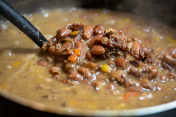 close up macro view of red beans and rice stew that was cooked for a tasty delicious dinner. the vegetables are vibrant with steam coming from the soup. a healthy organic meal was prepared.