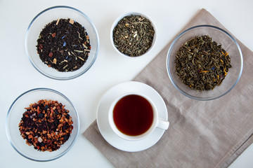 Assortment of dry tea in round bowls on a white background.
