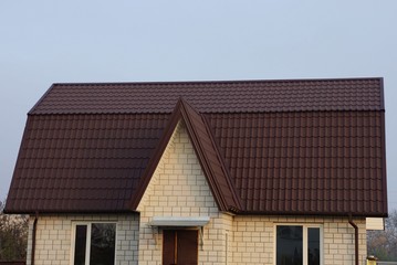 part of a private large white brick house with windows under a brown tiled roof 