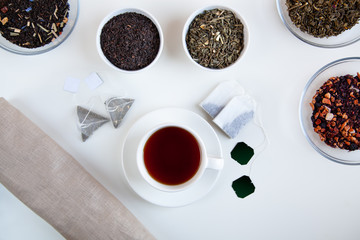 Assortment of dry tea in round bowls on a white background.
