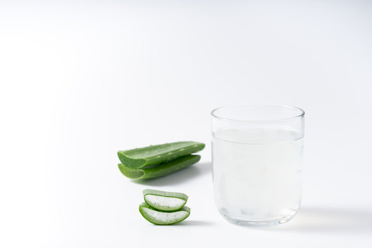 Cut aloe vera stem and gel in wooden bowl on white background