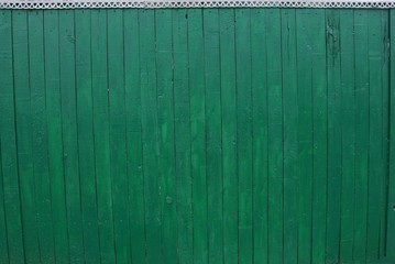 green wooden texture of thin old boards in the wall of the fence