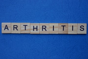 gray word arthritis from wooden small letters on a dark blue background