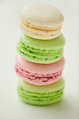 Vertical close up of delicious pastel-colored macaroons stacked in row on white background