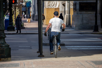 Chicago,IL/USA-April 18th 2020: man biking in the empty streets in the downtown Chicago area during the Covid-19 virus pandemic. the city is closed due to quarantine and business have stopped.
