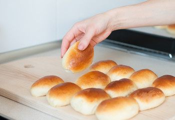 hands hold homemade patties pirozhki over wooden board with patties