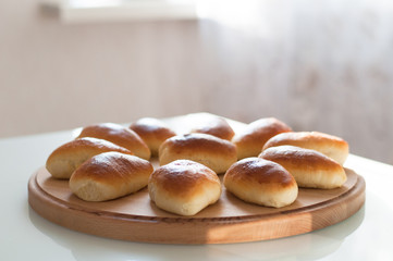 homemade patties pirozhki on round wooden board
