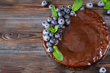 chocolate cake with fresh blueberries and mint on a dark brown wooden background, pie, top view