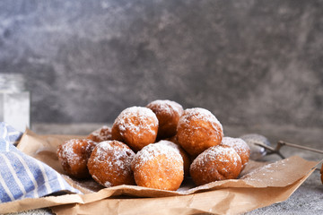 Fried donuts with icing sugar on the kitchen table.