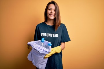 Beautiful volunteer girl caring environment doing volunteering holding bag with rubish bottles with...