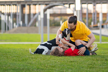 Fototapeta premium Happy family on summer walk. Dad, daughter and hunting dog have fun in park and playing together. Friendship between owner and pet. Funny expressive leisure time. Faithful friends of human.