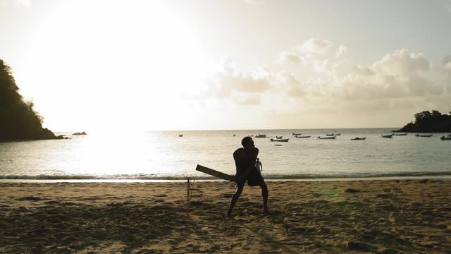 Young man playing cricket on the beach in Tobago.