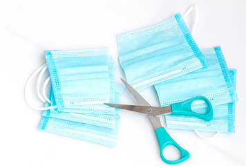 Close-up cut face mask and a pair of scissors on white background.To prevent reusing the face mask.