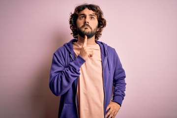 Young handsome sporty man with beard wearing casual sweatshirt over pink background Thinking concentrated about doubt with finger on chin and looking up wondering