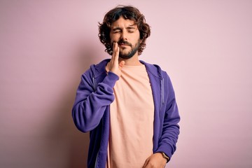 Young handsome sporty man with beard wearing casual sweatshirt over pink background touching mouth with hand with painful expression because of toothache or dental illness on teeth. Dentist