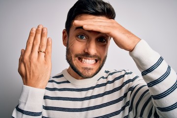 Handsome man with beard showing alliance ring marriage on finger over white background stressed...