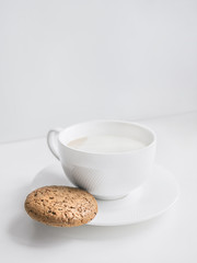 Cup of coffee Close-up photo with copy space Homemade coffee with milk in a white cup and oatmeal cookie with chocolate chips on the table