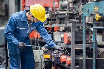 engineer checking metal component at machine receptacle in factory