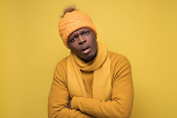 African man in warm hat and scarf looking at camera with confused expression