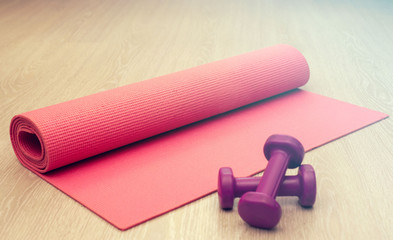 Pink fitness mat for home workouts and yoga and two dumbbells