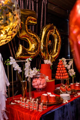 A candy bar with sweets in red tones for a woman who is fifty year old