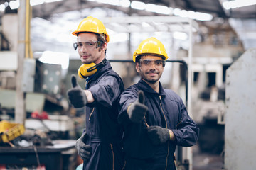 Good Job! technician and partnership smile and lokking camera at machine in factory