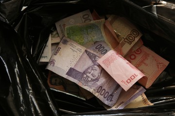 Banknotes from around the world inside a black plastic refuse bag. Money being wasted concept...