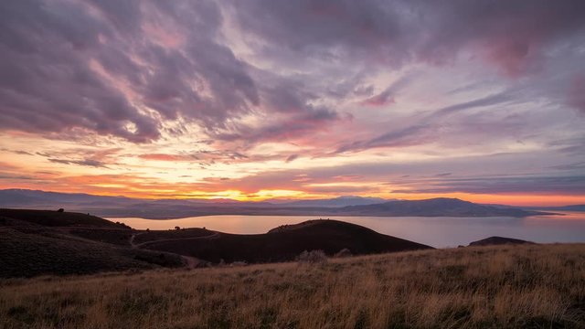 Colorful cloudy time lapse at sunset over Utah Lake from on top of West Mountain in Utah.