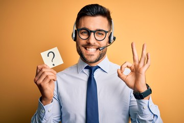 Business operator man with customer service headset from call center showing question mark doing ok sign with fingers, excellent symbol