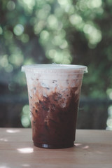 Cold coffee in a glass with milk cream over