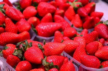 Heap of fresh strawberries in baskets ready for sale at marketplace.