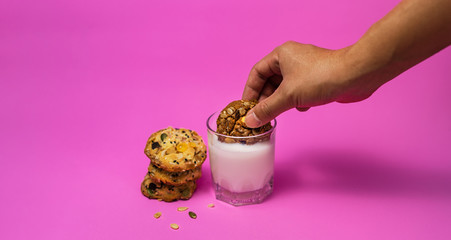 Cereal, chocolate, cookies and milk in a glass on a pink background