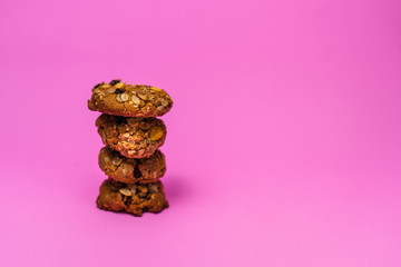 Cereal, chocolate, cookies and milk in a glass on a pink background