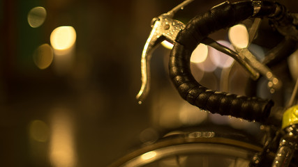 Rainy evening in the city. Shiny raindrops on a motorcycle mirror. Multi-colored city lights in the background. Creative evening lights and blurred shadows. Twilight mood. Close up.
