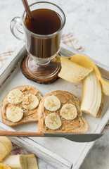 Sandwiches with peanut butter and banana and coffee close-up for breakfast
