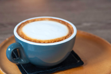 Hot cappuccino coffee with white cream foam serve in coffee cup set, lay on wooden round tray, classice coffee drink.